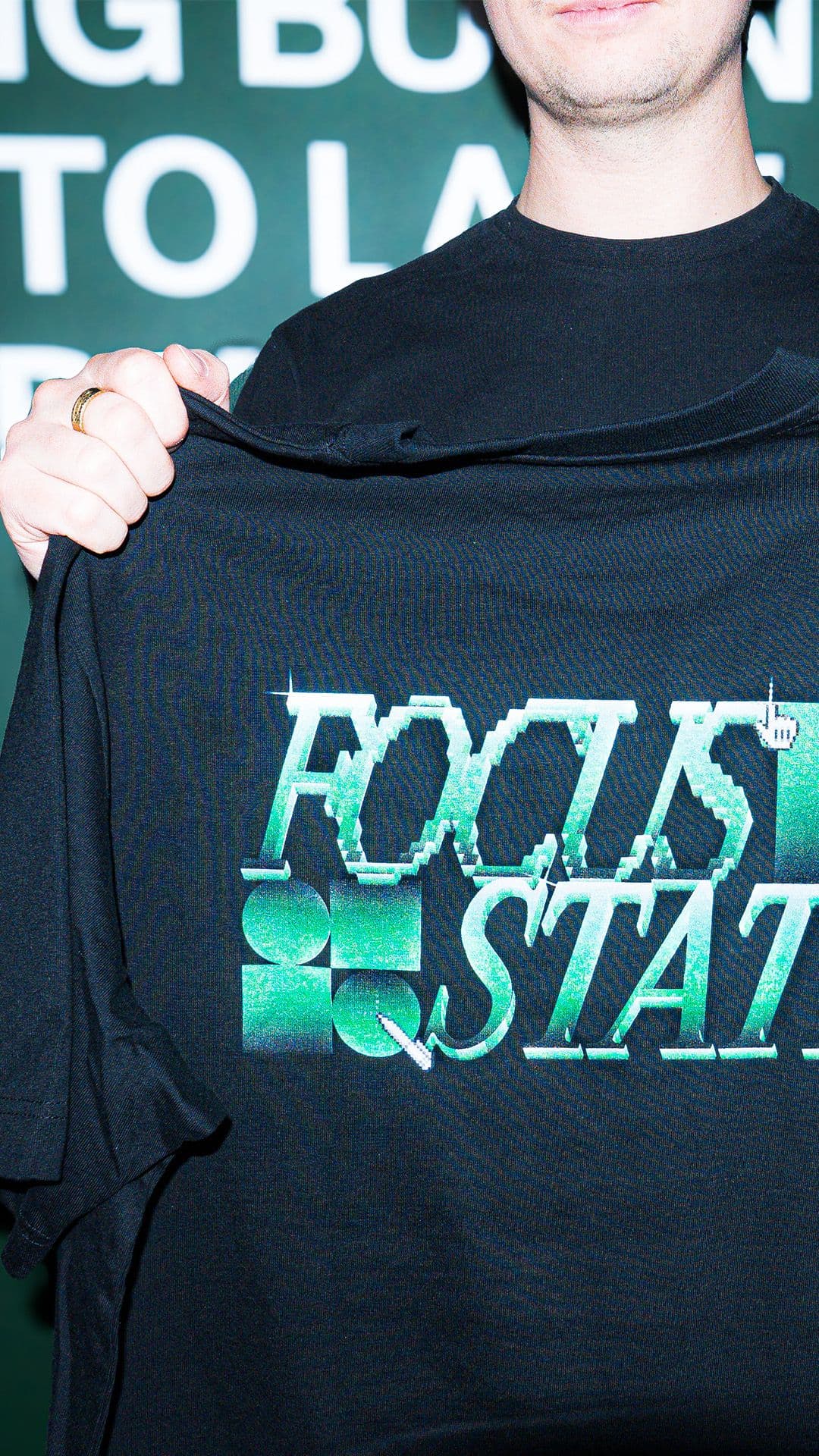 a man is holding a black t-shirt that says focus state