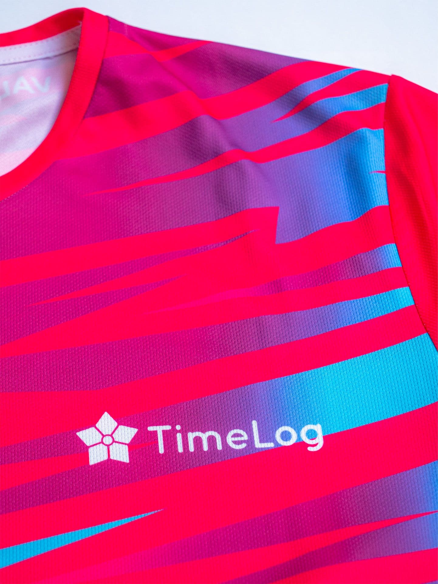 Close-up of a vibrant pink, purple, and blue striped athletic shirt featuring the white 'TimeLog' logo.