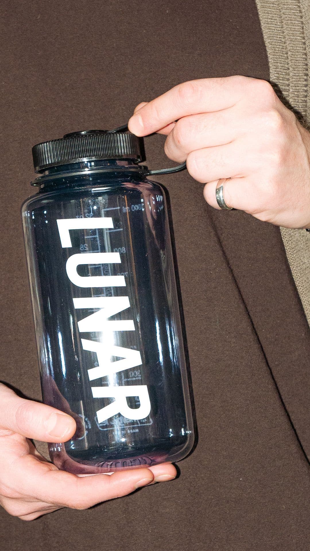 a person is holding a water bottle that says lunar on it